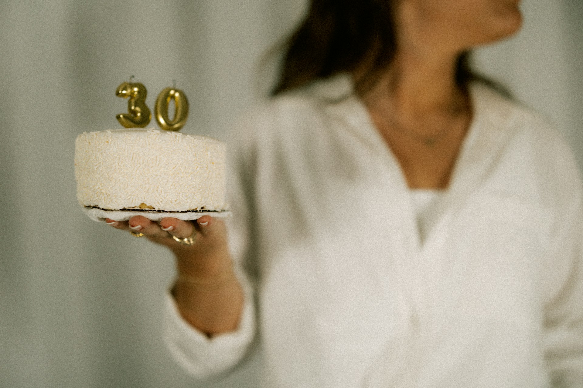 A woman holds a cake with the number 30.