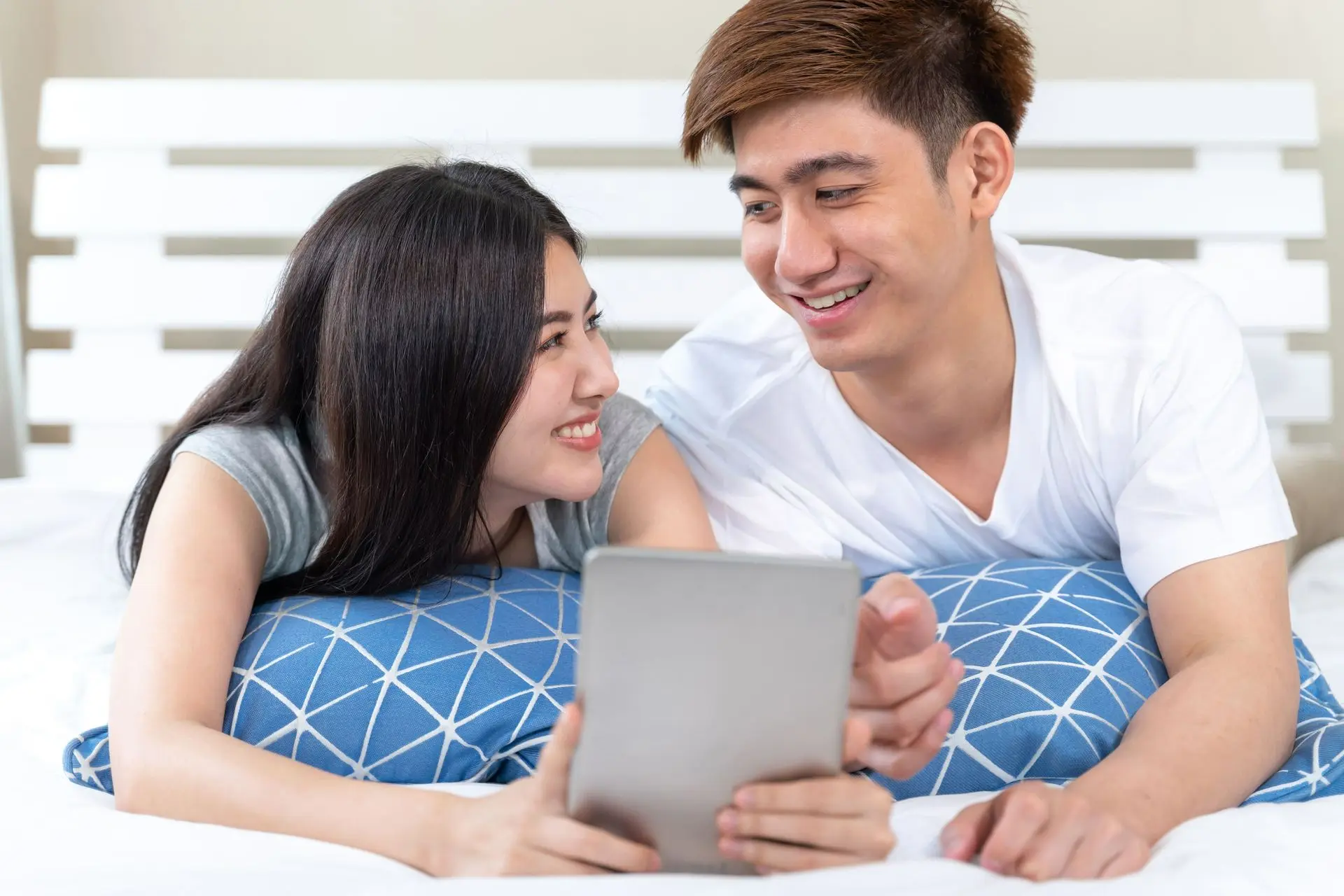 Cặp đôi vui vẻ nhìn nhau khi đang nằm trên giường