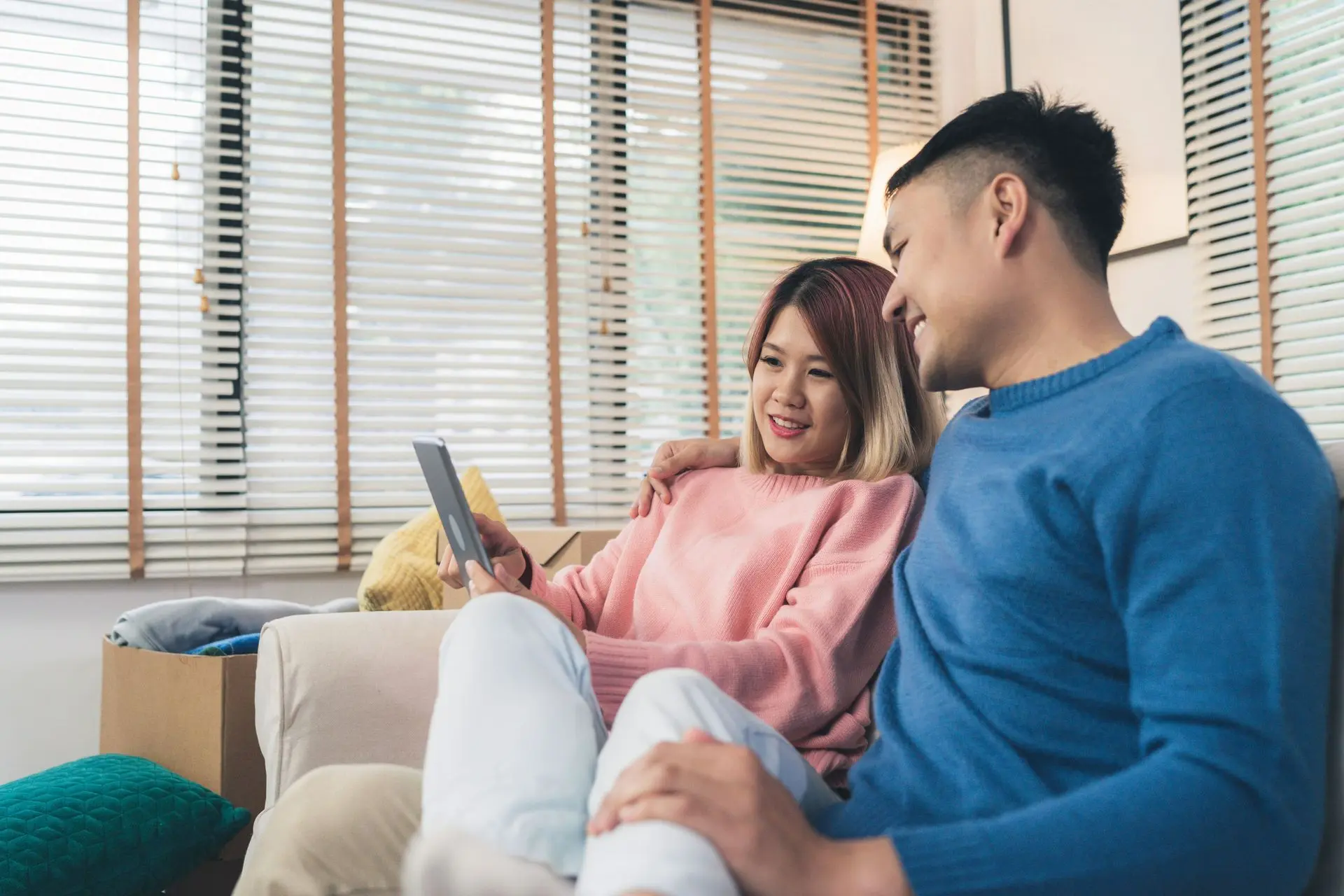 Cặp đôi nam nữ đang mỉm cười nhìn vào điện thoại